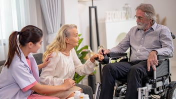 senior couple holding hands with nurse sitting nearby