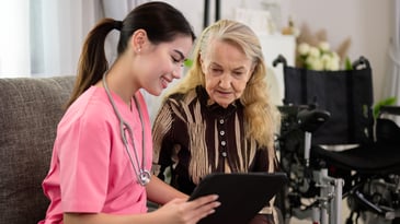 nurse and elderly woman looking at tablet for information, nursing home consulting