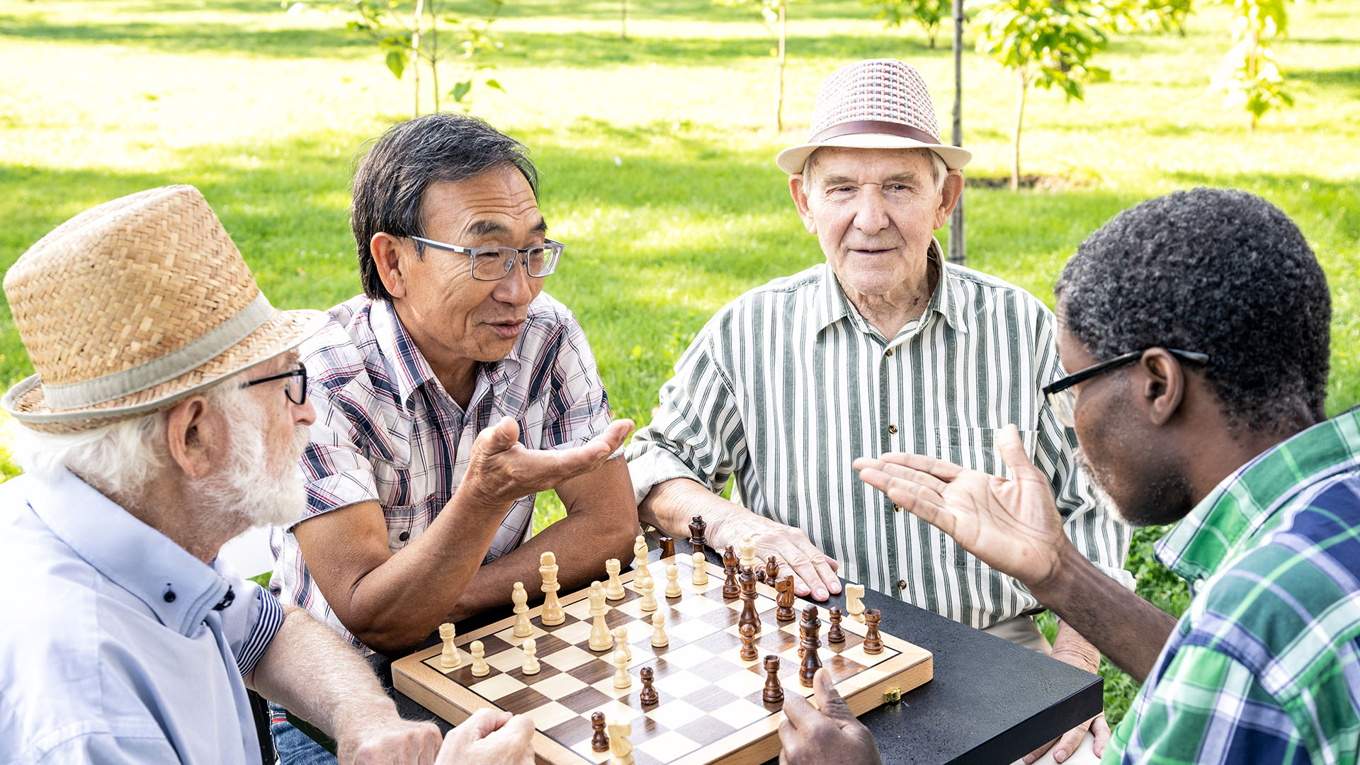 Seniors playing chess outdoors, nursing home consulting