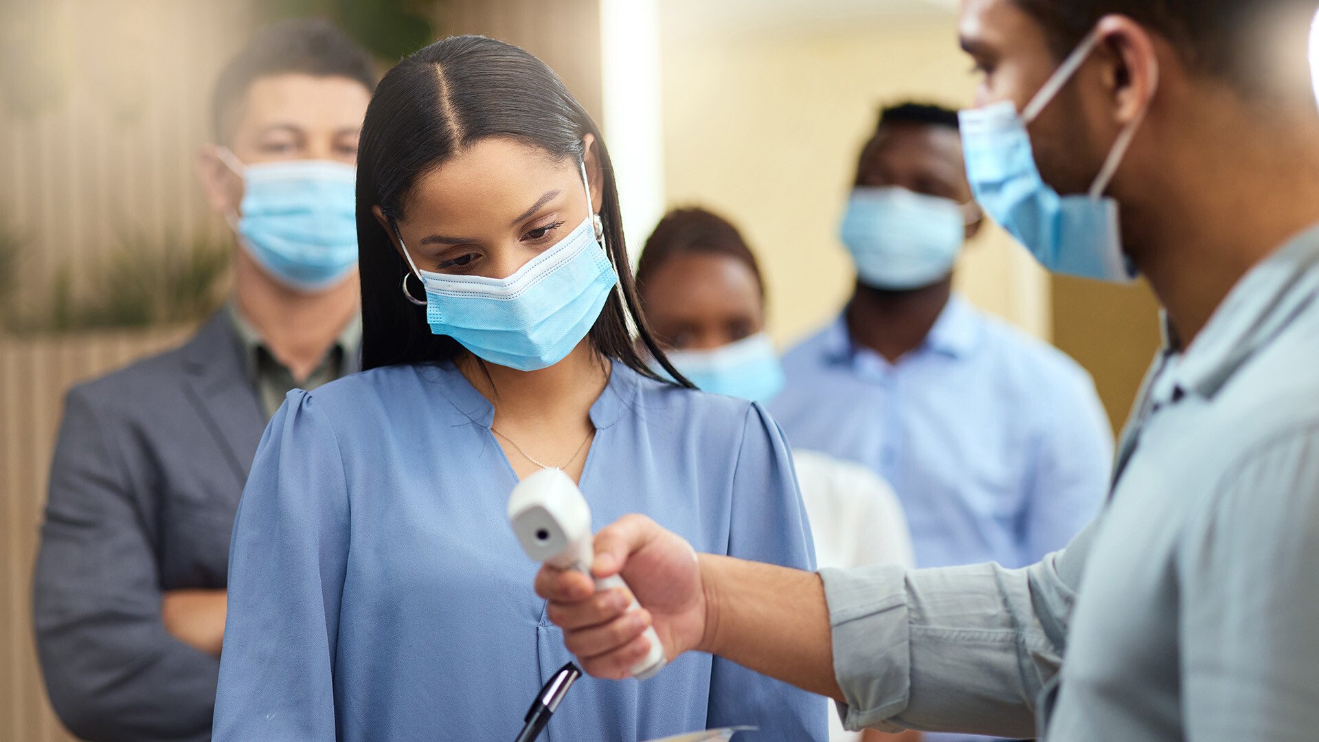 masked nurses with digital thermometer taking temperature