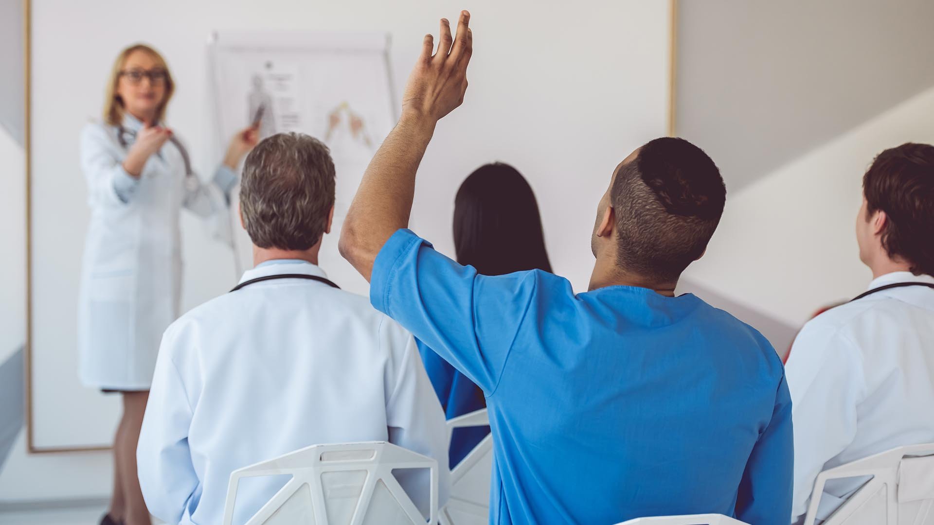 Nurses being taught, one man with hand raised asking a question